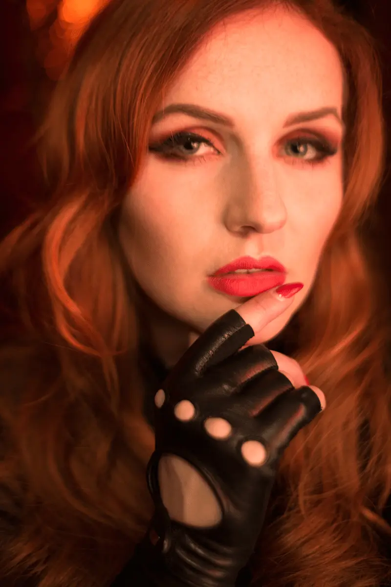 Frau mit roten Haaren und schwarzen Handschuhen, Fashion-Editorial in warmem Licht