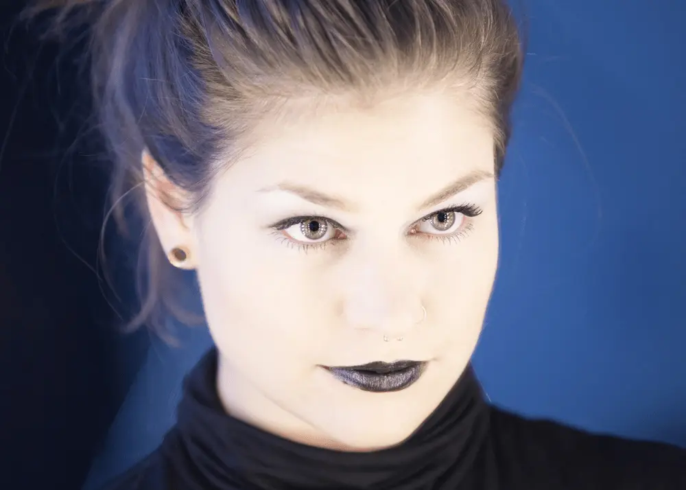 Portrait einer Frau mit dunklem Lippenstift vor blauem Hintergrund